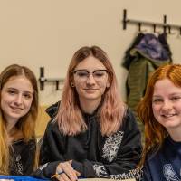 3 people smiling while painting a canvas at sibs and kids weekend
